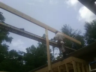 Carpenter setting a ridge beam over a new addition frame — Ice Dam Removal by Roofing Brothers in Dallas City