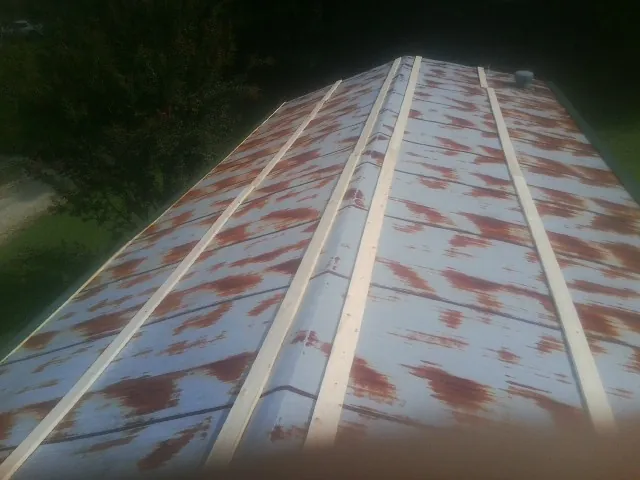 Rusted metal roof panels with new wood purlins before replacement — Storm Damage Roof Repair in Dallas City by Roofing Brothers
