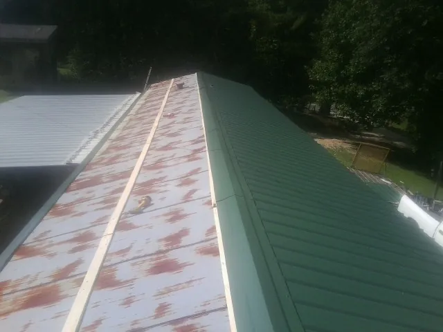 Old rusted panels beside newly installed green metal roofing — Wind Damage Roof Repair by Roofing Brothers in Dallas City