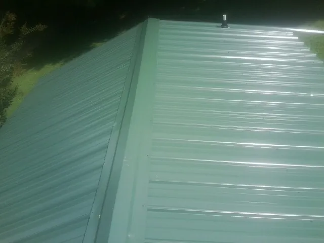 New green metal panels meeting at the ridge of a roof — Flat Roof Repair work by our crew in Dallas City