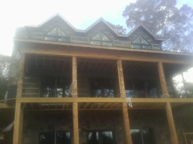Dormers and porch framing on a large log home under construction — Roof Coating work by our crew in Dallas City