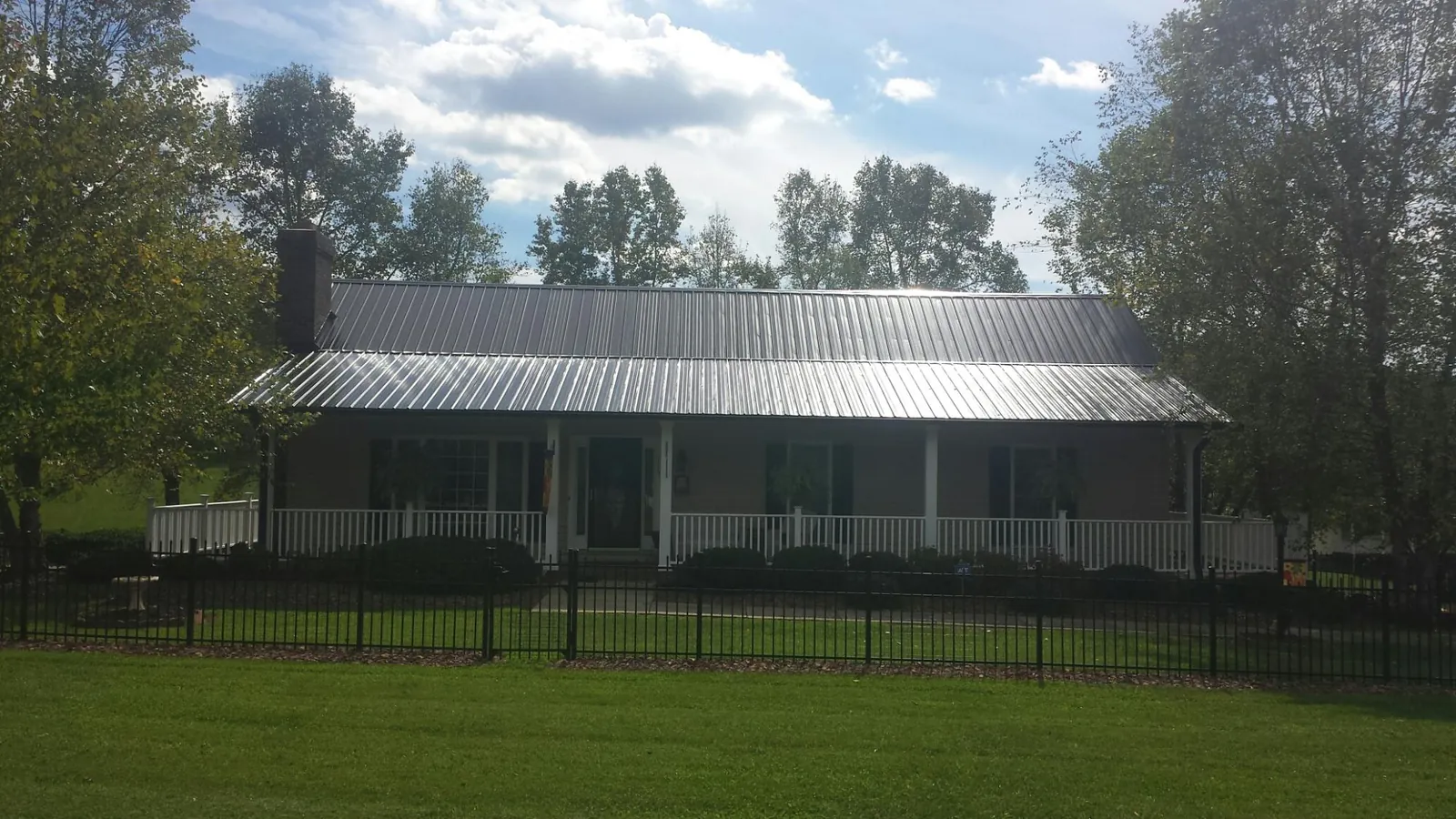 Gray metal roof on a brick ranch with a full width front porch — Gutter Guard Installation work by our crew in Dallas City