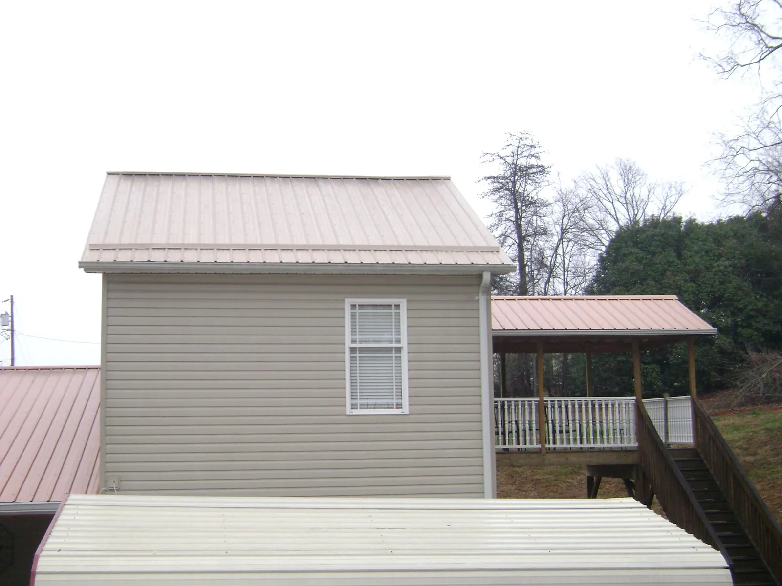 Tan metal roofs on a two story addition and attached porch, from a Roof Replacement job in Dallas City