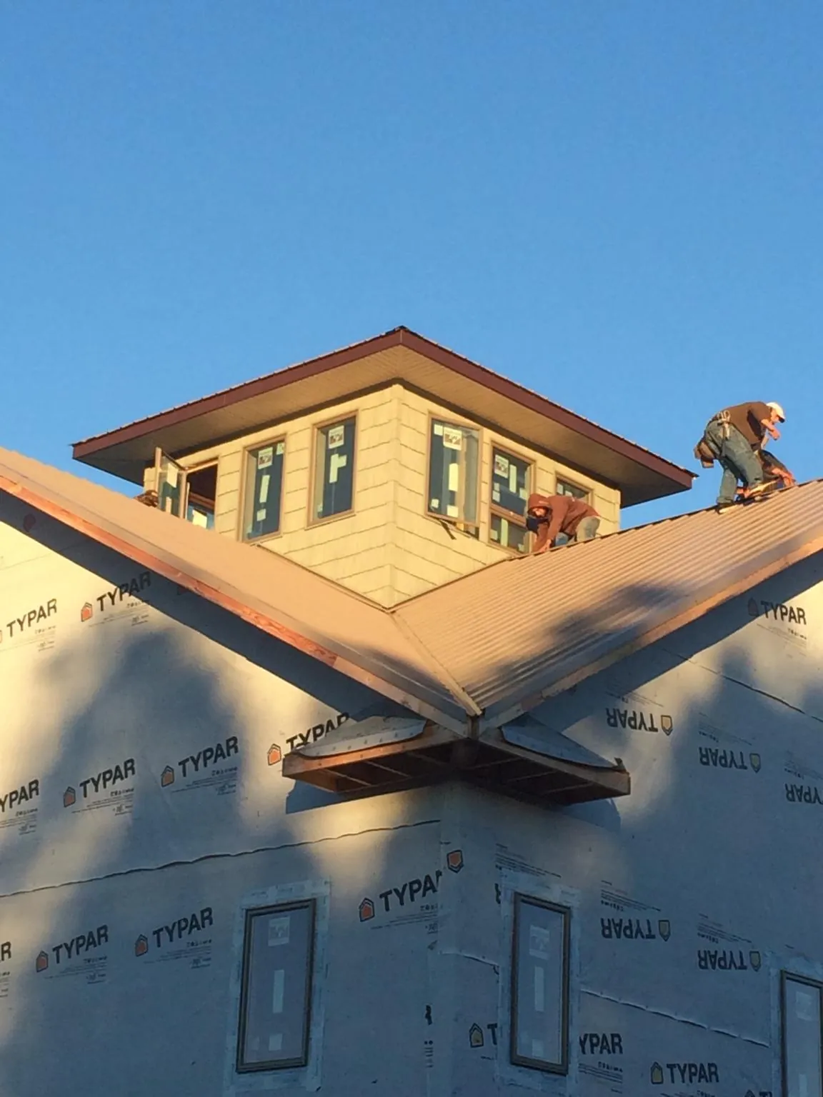 Roofers working around a rooftop cupola on a new metal roof at sunset — Roof Waterproofing in Dallas City by Roofing Brothers